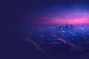 A futuristic-looking cityscape at sunset with a glowing violet-blue sky. Luminous, digital connecting lines run above the high-rise buildings, symbolizing a networked, smart cityscape