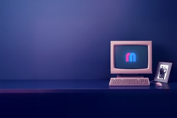 Ein Retro-Computer-Setup auf einem Tisch mit einem gerahmten Foto daneben in einem purpur beleuchteten Raum.