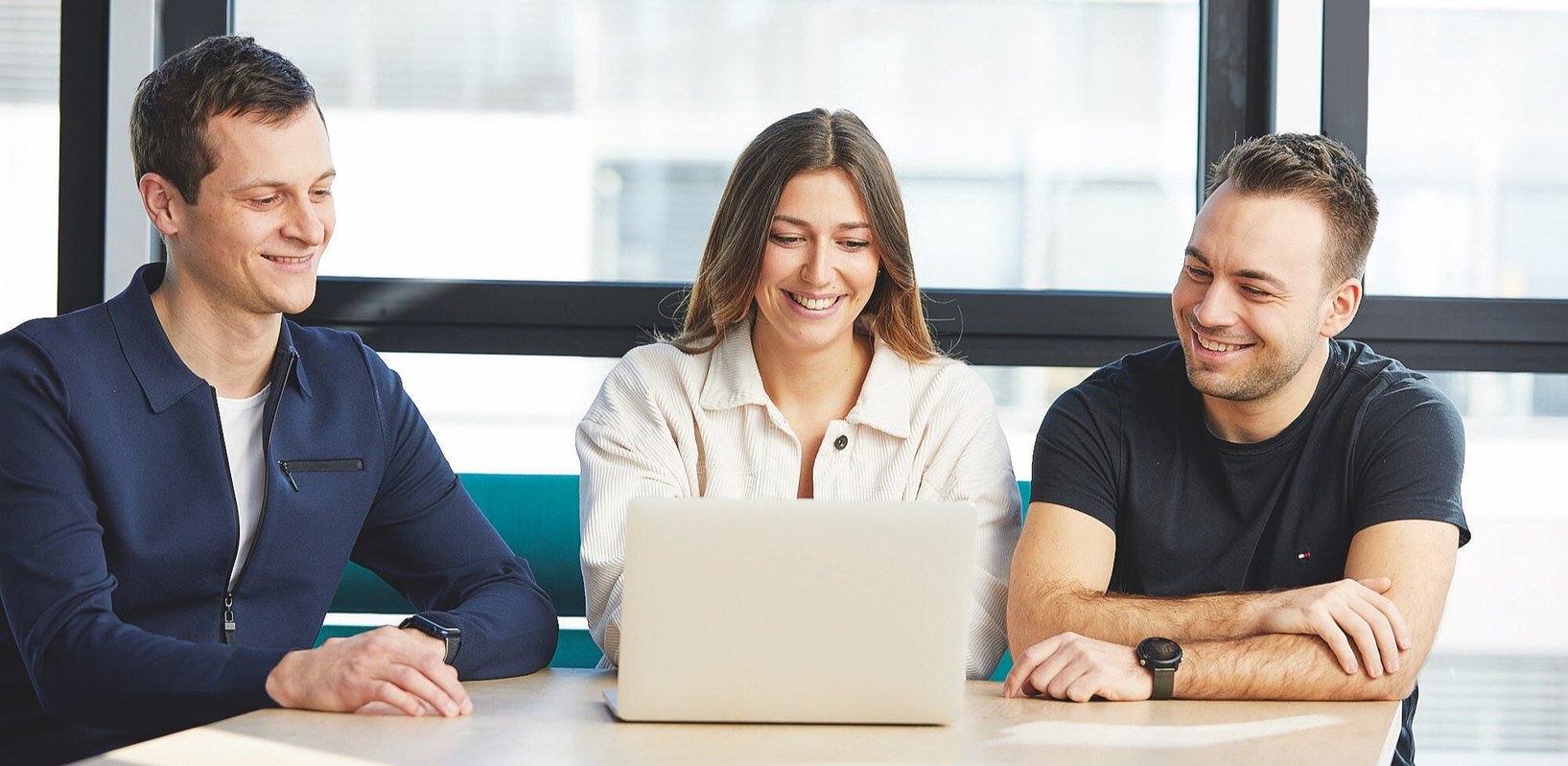 Team meeting with three people at the laptop.