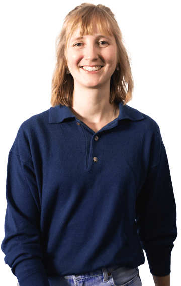 Eine Person mit mittelblondem Haar trägt ein dunkelblaues Oberteil und hellblaue Jeans.