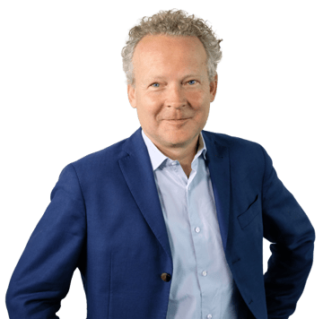 Eine Person in einem formellen blauen Blazer mit einem hellblauen Hemd posiert vor einem neutralen Hintergrund.